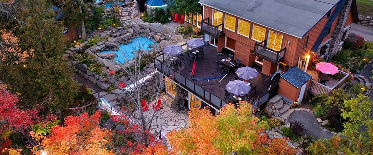 Vue aérienne de l'Auberge & Spa Beaux Rêves et de son espace spa en automne, montrant les terrasses et les bassins nichés dans la forêt colorée.