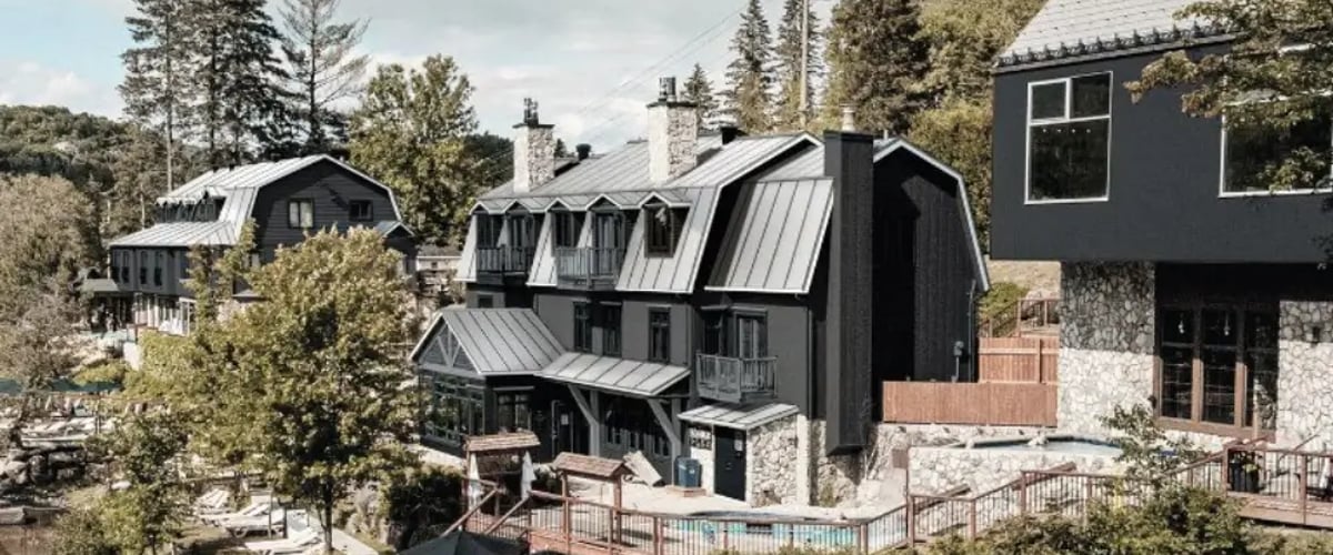 Vue d'ensemble du complexe Strøm Spa Nordique à Saint-Sauveur, montrant les différents bâtiments et terrasses qui longent la rivière à Simon.