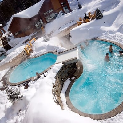 Vue d'ensemble des piscines extérieures chauffées de l'Amerispa Spa Nordique Morin-Heights entourées de neige.