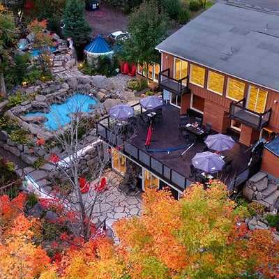 Vue aérienne de l'Auberge & Spa Beaux Rêves et de son espace spa en automne, montrant les terrasses et les bassins nichés dans la forêt colorée.