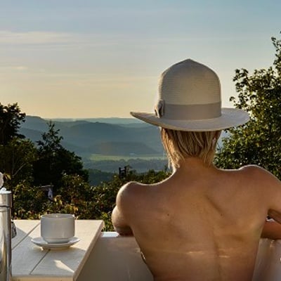 Femme relaxant dans un bain extérieur avec vue sur les montagnes à l’Eco Spa Highland Laurentides.