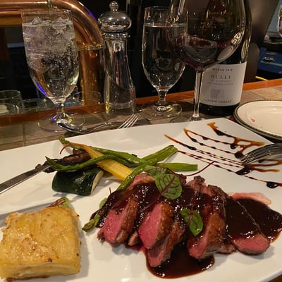Assiette gastronomique et verre de vin rouge servis au restaurant du Spa Auberge du Lac Morency.