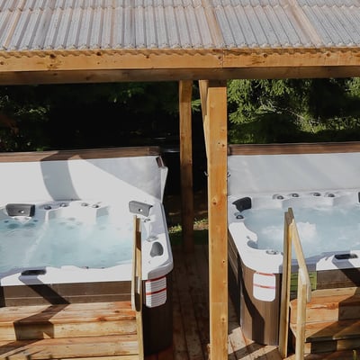 Deux bains à remous extérieurs situés sous un abri en bois à l'Excelsior Hôtel Spa, pour une utilisation en toute saison.