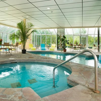 L'espace piscine intérieure de l'Excelsior Hôtel Spa, avec ses bains à remous et sa grande verrière lumineuse donnant sur la nature.