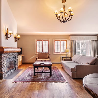 Intérieur d'une suite luxueuse au Manoir Saint-Sauveur, avec un salon, un foyer en pierre et un décor chaleureux.