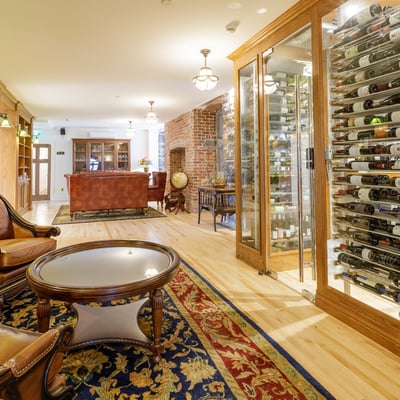 Salon luxueux du Spa StoneHaven Le Manoir avec cave à vin et fauteuils en cuir dans une atmosphère raffinée.