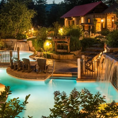 Les piscines et chutes du Scandinave Spa illuminées à la tombée de la nuit, créant une atmosphère féerique et intime.