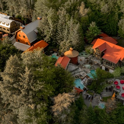 Vue aérienne du complexe complet du Scandinave Spa Mont-Tremblant en été, montrant les différents pavillons et piscines intégrés dans la forêt dense.