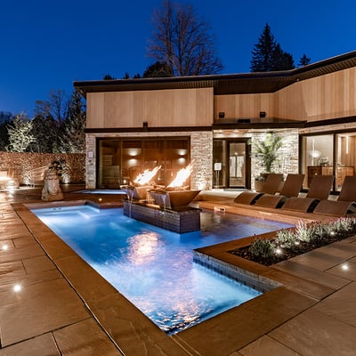 L'espace thermal exclusif du Spa du Manoir Saint-Sauveur illuminé en soirée, avec ses foyers intégrés à la piscine.