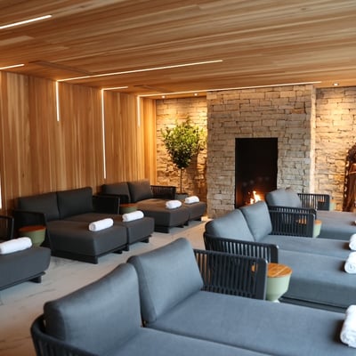 La salle de relaxation du Spa du Manoir Saint-Sauveur, avec ses lits de jour confortables et son foyer en pierre chaleureux.