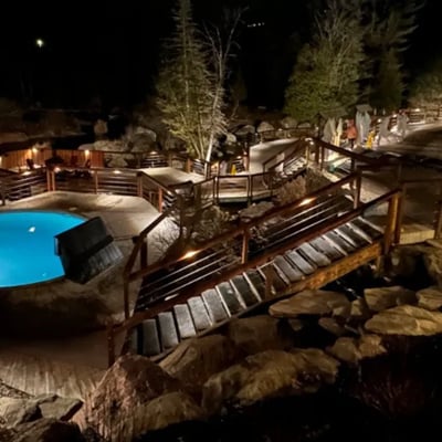 Vue nocturne des bains extérieurs et des passerelles illuminées du Strøm Spa Nordique à Saint-Sauveur, créant une ambiance chaleureuse.