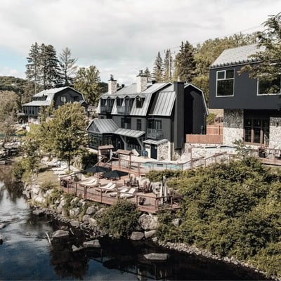 Vue d'ensemble du complexe Strøm Spa Nordique à Saint-Sauveur, montrant les différents bâtiments et terrasses qui longent la rivière à Simon.