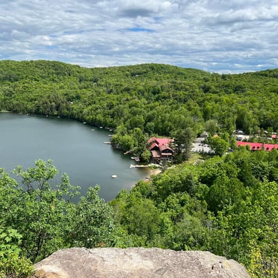 Vue aérienne du Spa Auberge du Lac Morency et du lac entouré de forêts verdoyantes.