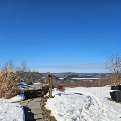 Panorama d’hiver à l’Eco Spa Highland Laurentides avec montagnes et ciel bleu clair.