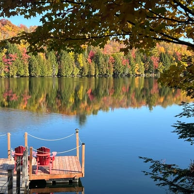 Quai en bois et chaises Adirondack au bord du lac automnal du Spa Auberge du Lac Morency.